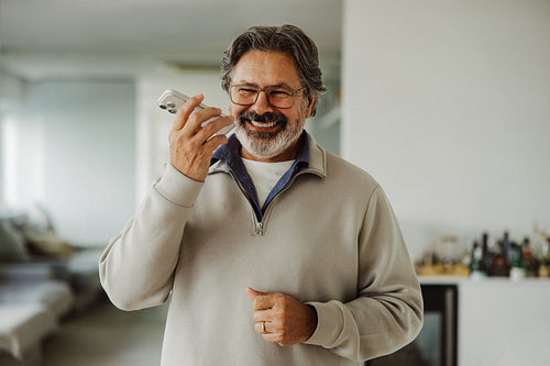 Senior man talks on smartphone at home