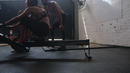Woman exercising on row machine with trainers