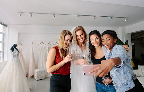 Bride with friends taking selfie in bridal boutique