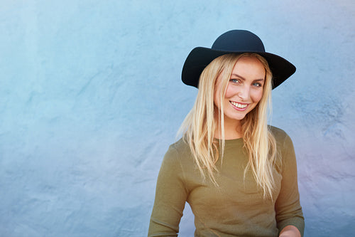 Beautiful smiling woman posing by blue wall