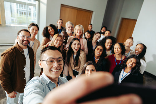 Diverse group taking a cheerful selfie at a successful seminar to capture a memorable moment of teamwork and collaboration