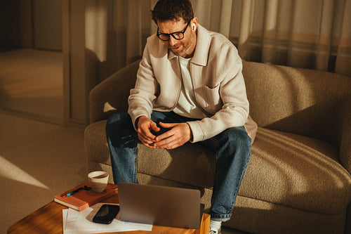 Businessman on video call from sofa in minimalist workspace