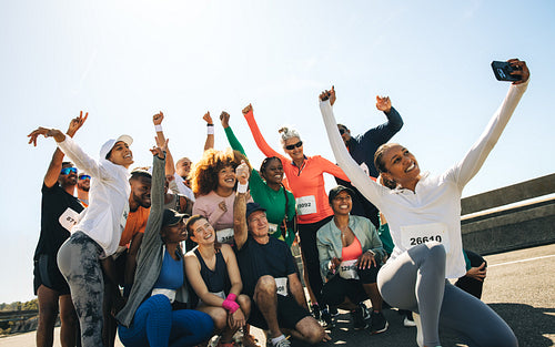 Group of diverse runners celebrating with a selfie after a race