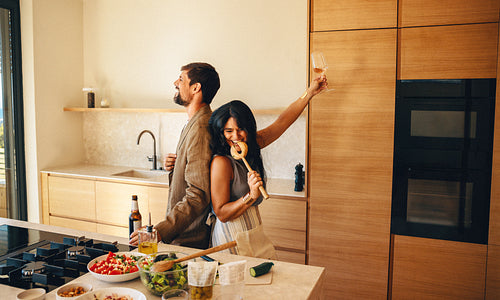 Couple cooking in a modern kitchen while enjoying fun and drinks