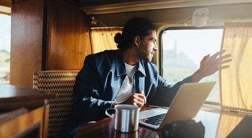 Scenic pause: Man reaches toward the window while working in the camper van