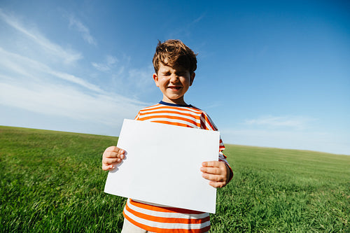 Boy holding blank sign outdoors for message or creativity