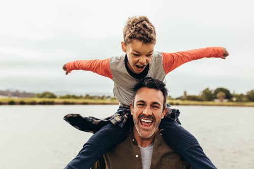 Happy dad and daughter are sitting on grass near water and looking at  camera. He is huging her and holding fish-rod in right hand. They are  fishing Stock Photo - Alamy