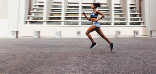 Woman runner in jogging outfit running on a street. Woman