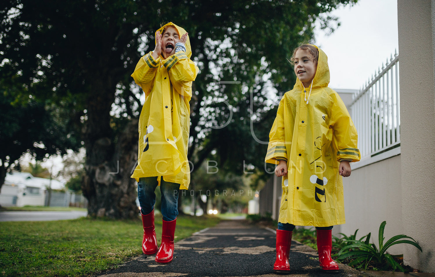 Identical twin sisters having fun outside on a rainy day
