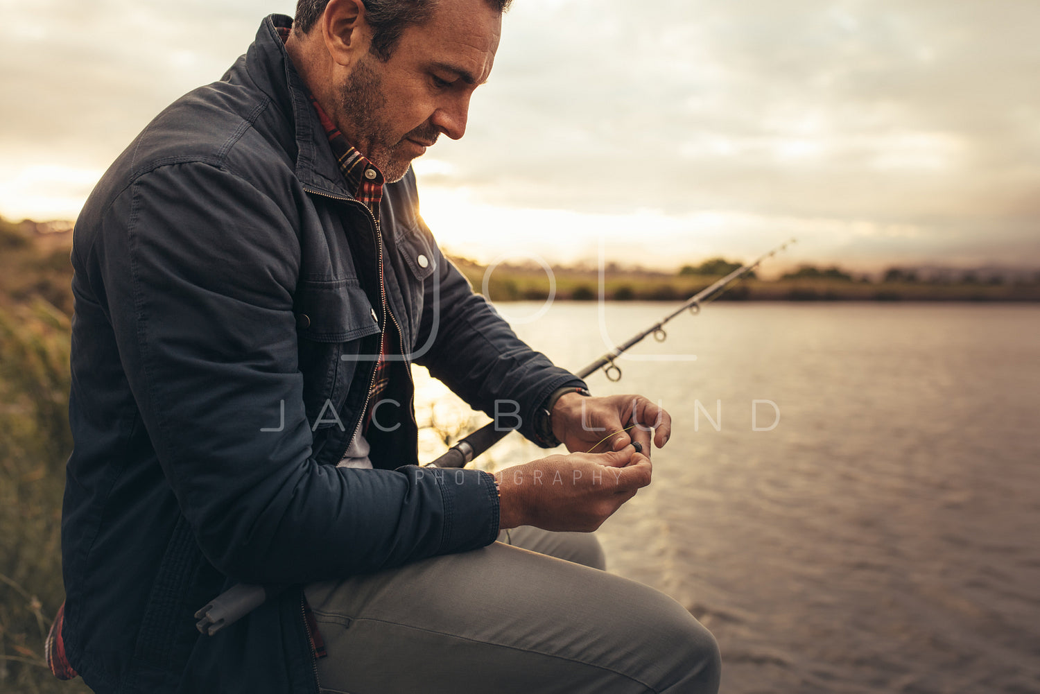 Man sitting near a lake with fishing rod