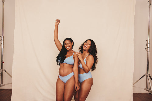 Two young women embracing their natural bodies while wearing brown  underwear stock photo