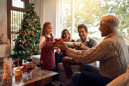 A little girl enjoys a lot of Christmas gifts sitting on the couch at home.  Stock Photo by puhimec