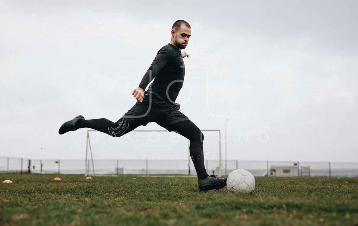 Footballer kicking the ball on field – Jacob Lund Photography Store-  premium stock photo