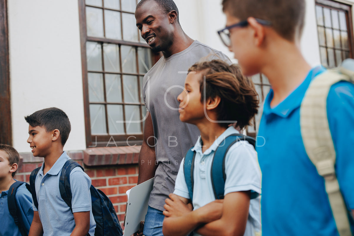 Male School Teacher Walking Outside Class With His Students – Jacob 