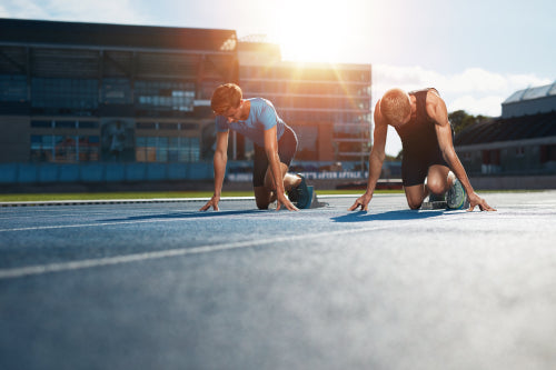top view of young adult male athlete in low start position at athletic  track. start line position. copy space Stock Photo