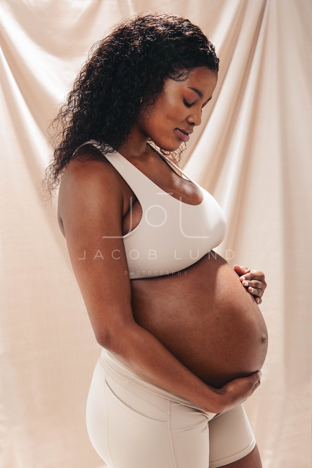 Two pregnant women wearing underwear in a studio, showing their