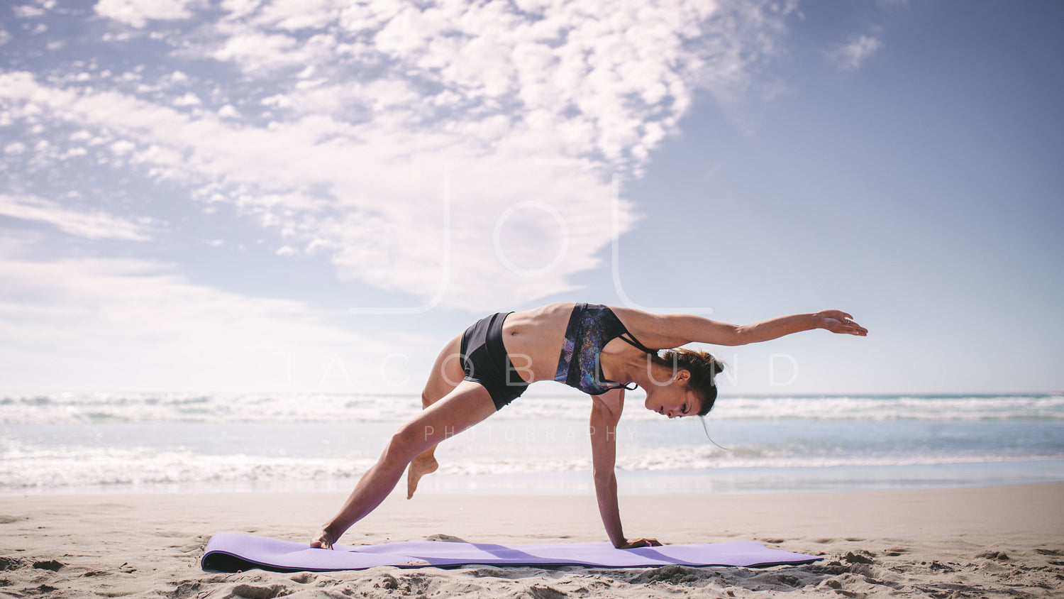 Sporty woman doing king pigeon yoga pose on the beach stock