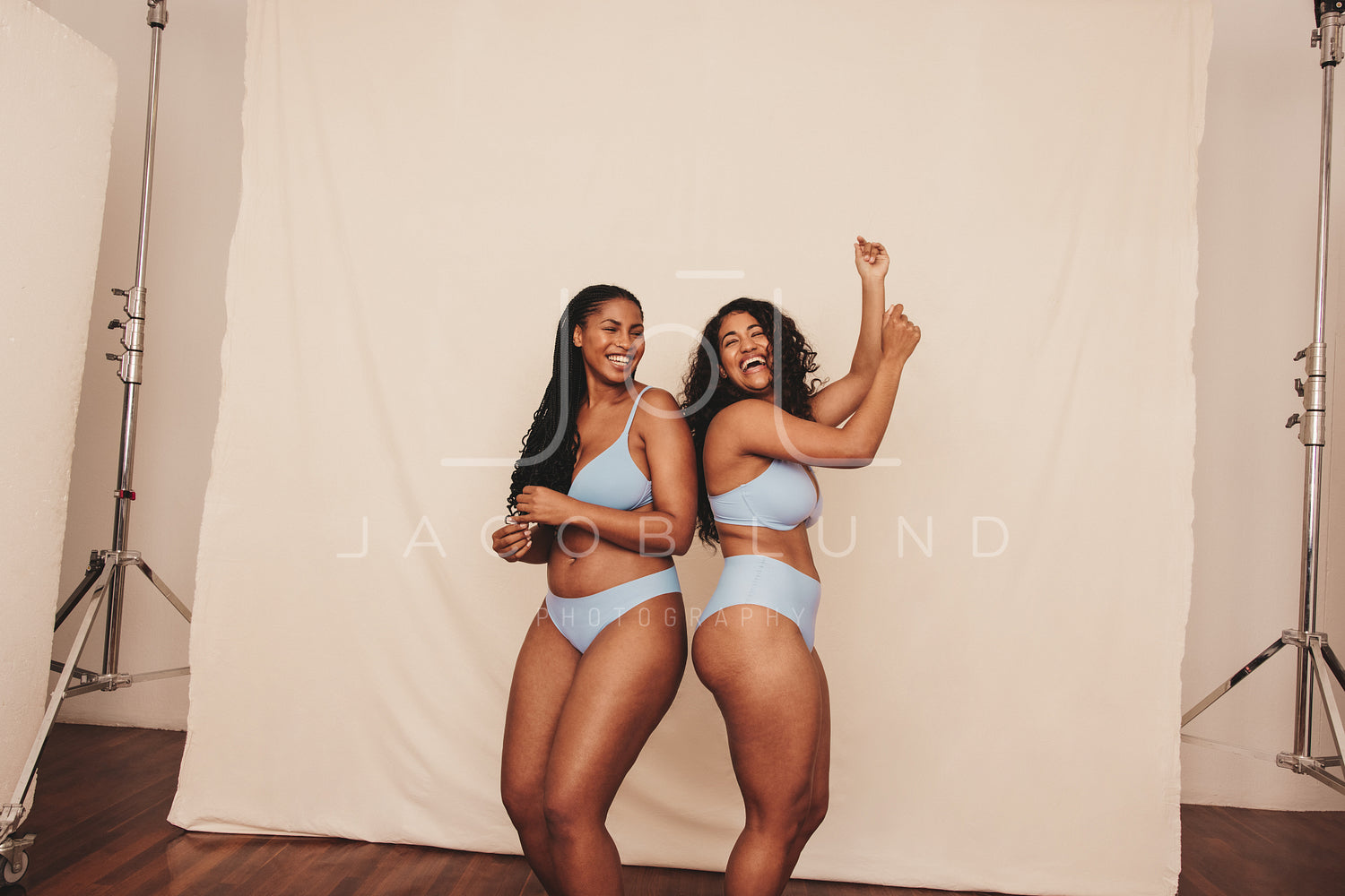 Cheerful young women dancing while wearing blue underwear