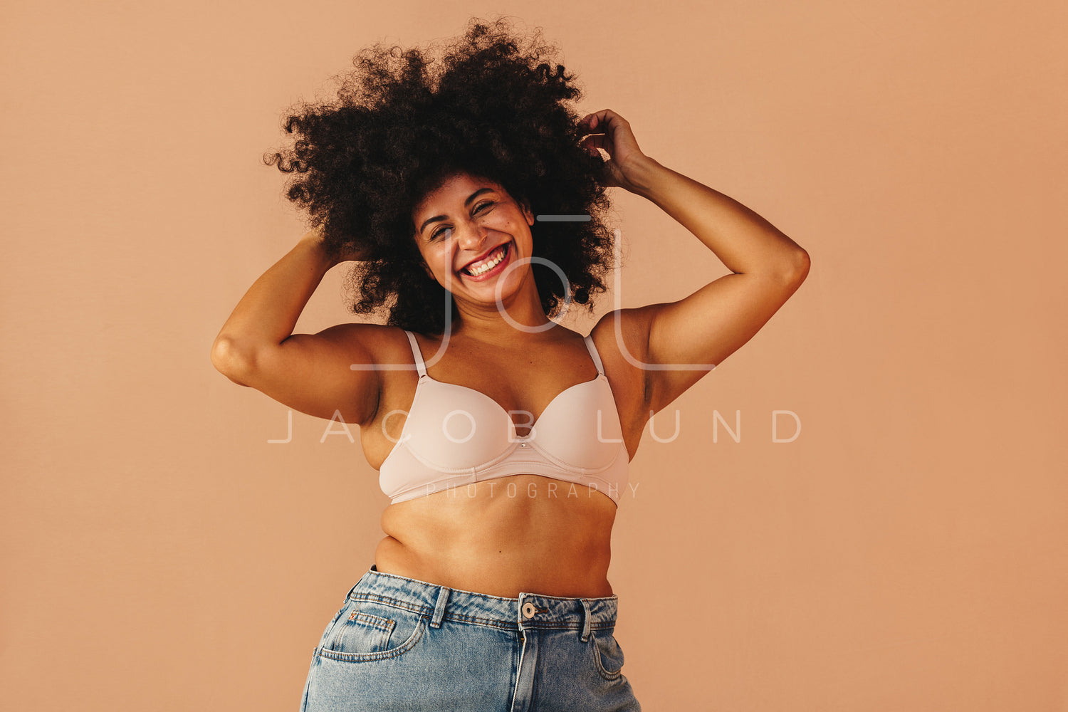 Beautiful black woman with an afro hairstyle wear white bra and blue jeans  looking at camera and smiling Stock Photo