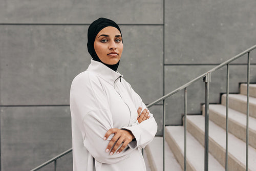 Sporty woman with a hijab warming up by doing stretch exercises outdoors in  the morning. Athletic