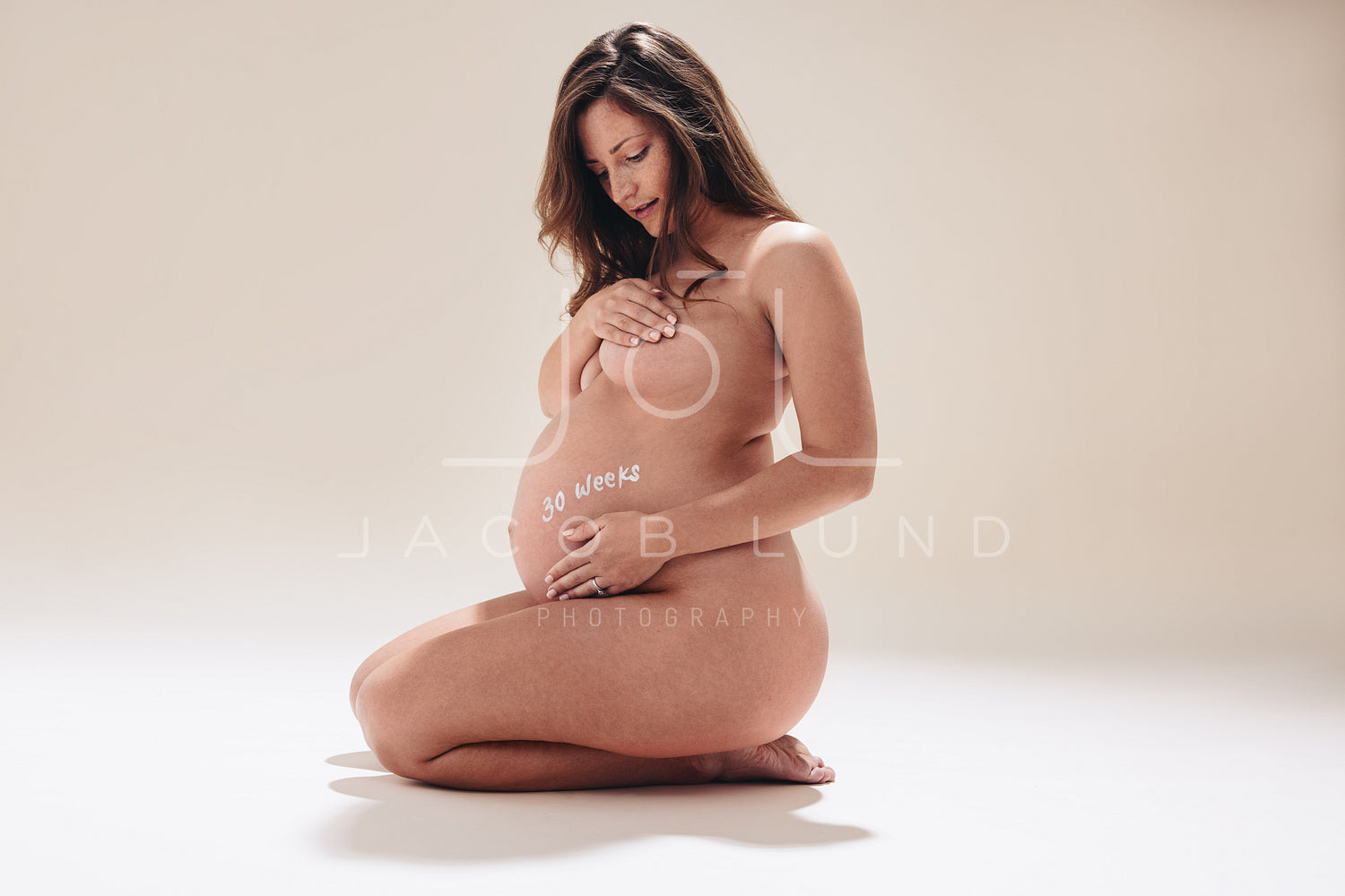 Confident pregnant woman embracing her baby bump in the third trimeste –  Jacob Lund Photography Store- premium stock photo