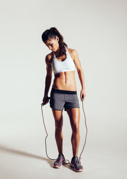 Fotografia do Stock: Young woman smiling confident wearing sports bra  standing on city park, outdoors holding a skipping rope on her neck looking  at the camera during work out.