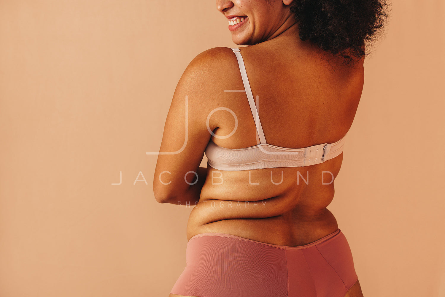 Back view of a happy curvy woman wearing underwear in a studio