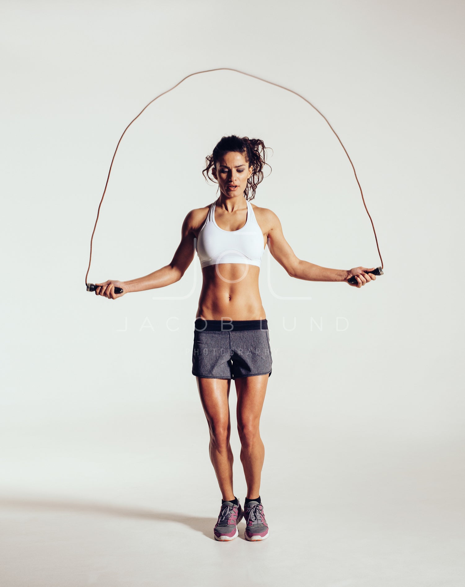 Female athlete in training clothes doing workout holding a skipping rope.  stock photo