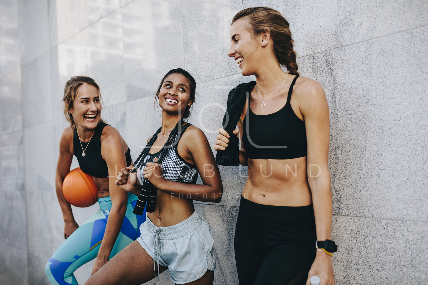 Fitness women relaxing after workout standing against a wall