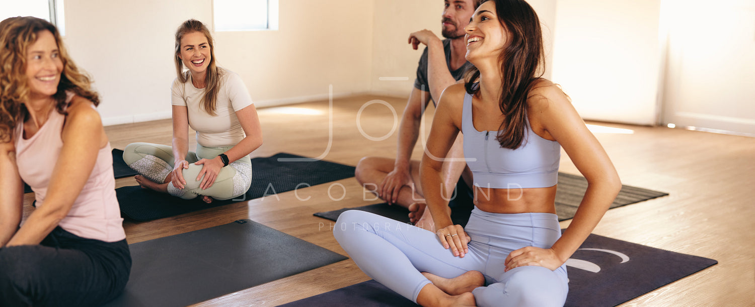 Women laughing together while sitting on yoga mats in a fitness