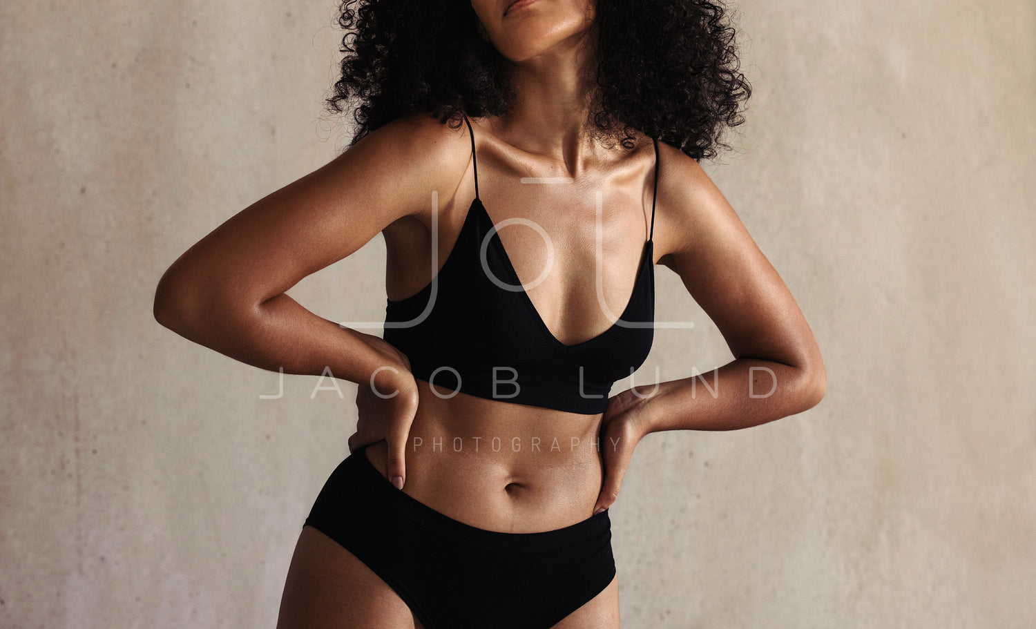 Mature woman embracing her natural and aging body. Confident woman wearing black  underwear and smiling cheerfully while standing alone against a studio  background. stock photo