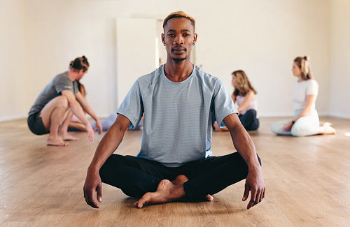 Portrait of young happy black man and a group of sporty people practicing  yoga lesson standing