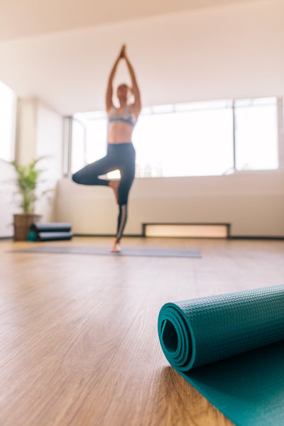 Yoga mat in fitness center with woman meditating at back – Jacob Lund  Photography Store- premium stock photo