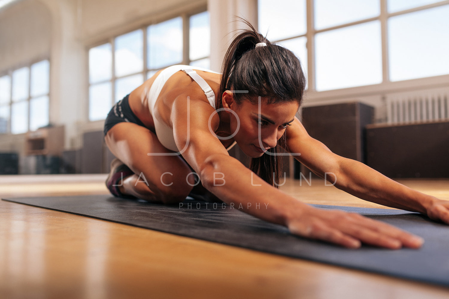 Muscular woman doing stretching workout in gym – Jacob Lund