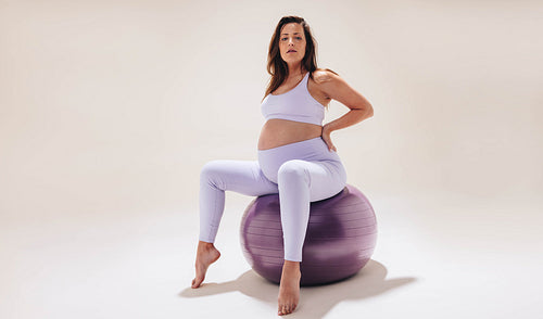 Woman in yoga pants sitting on a bouncy ball Stock Photo by