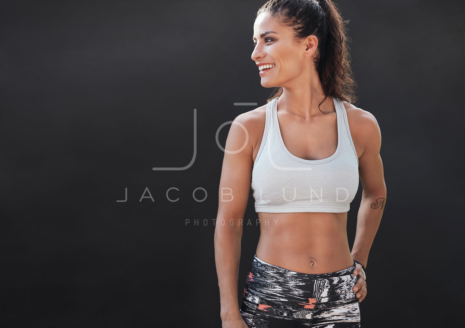 Happy young woman in sports clothing smiling – Jacob Lund