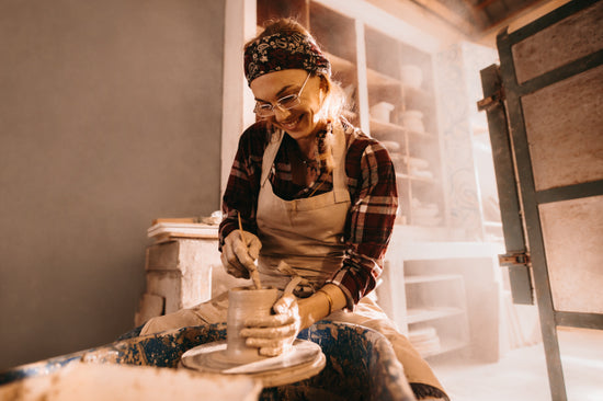 Midsection of woman molding clay in pottery wheel stock photo