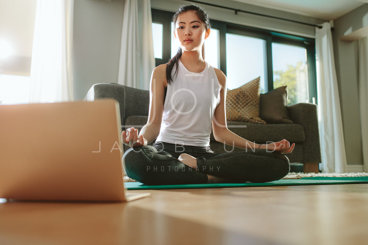 Premium Photo  Asian young woman practicing yoga on mat while sitting in  front of her laptop computer at home.