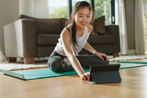 Woman Doing Yoga While Watching Instructional Videos On Laptop