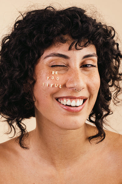 Unshaven young woman smiling cheerfully while wearing a bra and jeans.  Happy young woman embracing her natural body and underarm hair. Body  positive young woman making her own choice about her body.