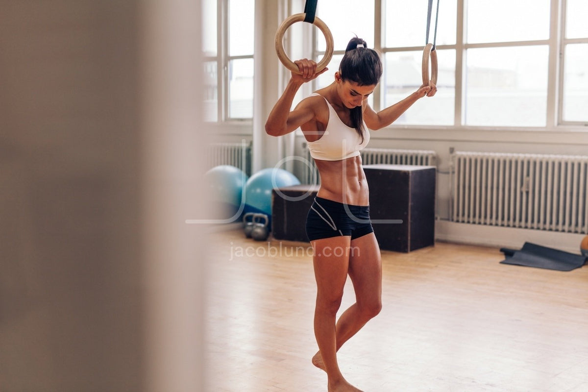 Woman exercising with gymnastic rings in gym – Jacob Lund