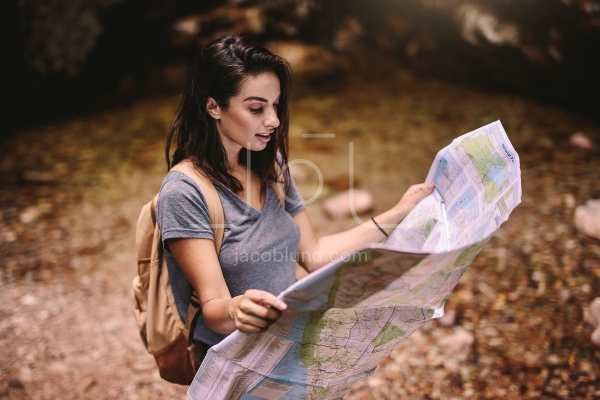Female hiker in forest reading a map