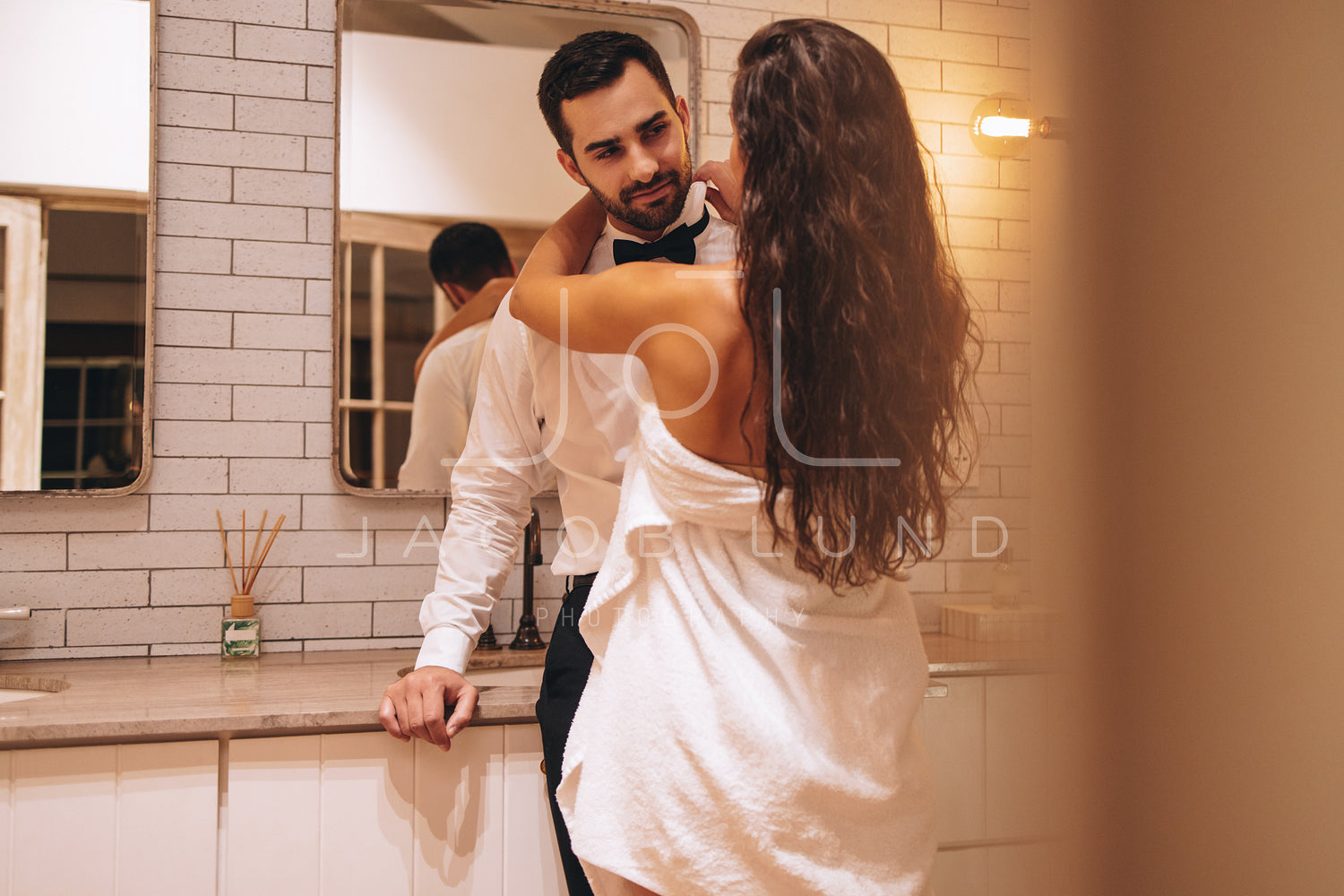 Romantic wife fixing her husbands shirt in a hotel dressing photo