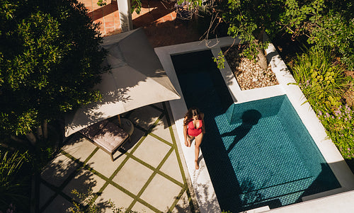 Woman taking off her gown near a swimming pool. Rearview of an